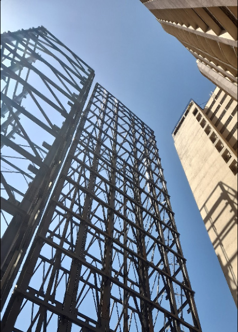 Steel tower parking structure rising alongside a building
